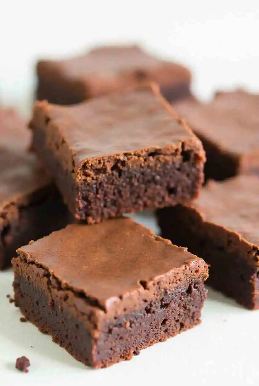 A batch of freshly baked Nutella brownies cooling on a wire rack, with a spoon and a jar of Nutella in the background.